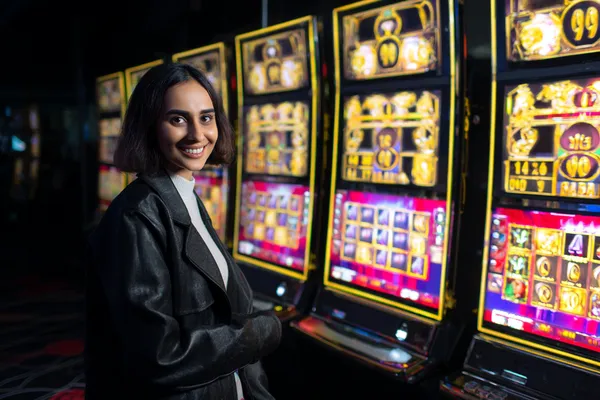 A woman smiling while playing online games on her laptop, surrounded by neon casino elements, showcasing OKTKBD’s diverse game collection.